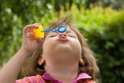 Girl blowing bubbles using homemade bubble solution