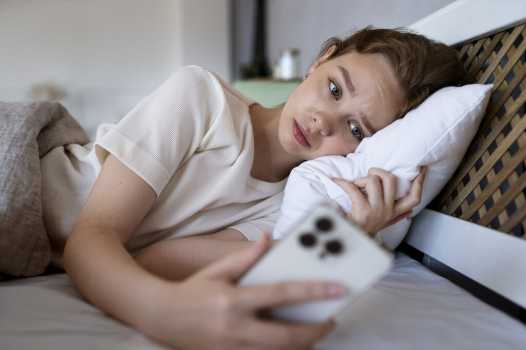Teen lying in bed looking at a phone